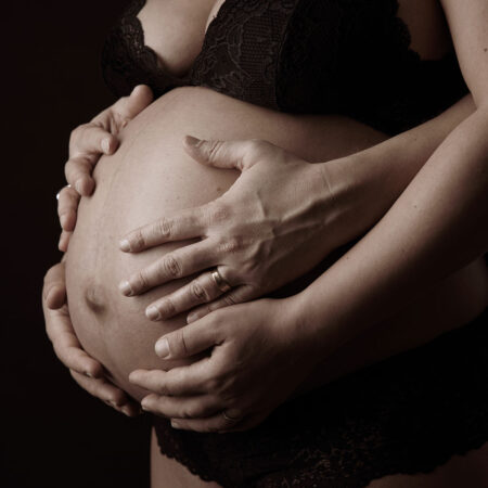 babybauchfoto im Studio fotografiert mit Händen der Eltern auf dem Bauch