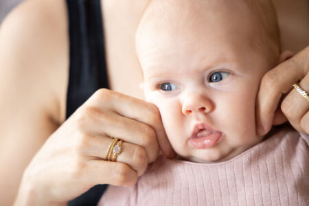 natürliches babyportrait, ganz nah, mit Händen der Mutter, die die süßen dicken Backen drücken