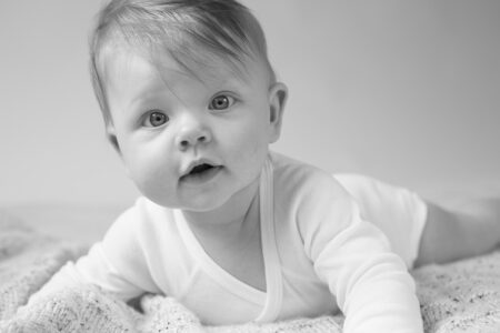 süßes babyportrait im weißen body auf kuscheldecke