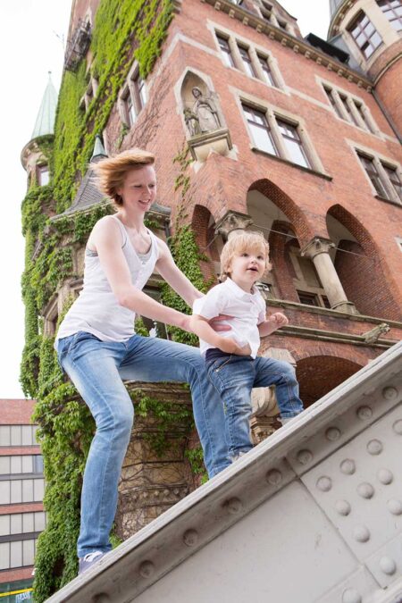 tante mit kleinkind klettert auf brückengeländer in der speicherstadt in hamburg