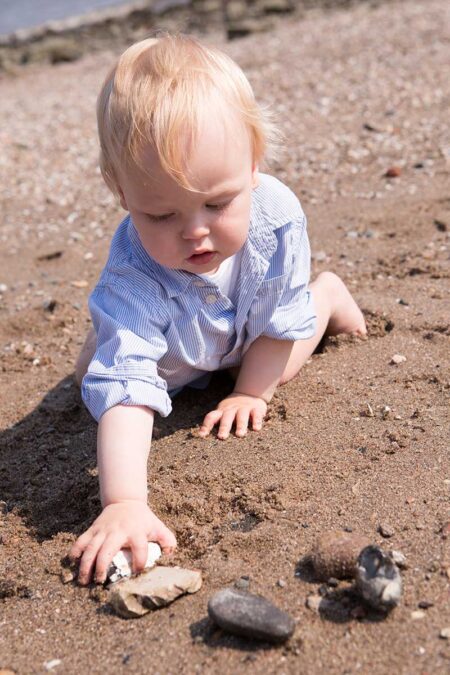 baby greift nach einem stein am elbstrand