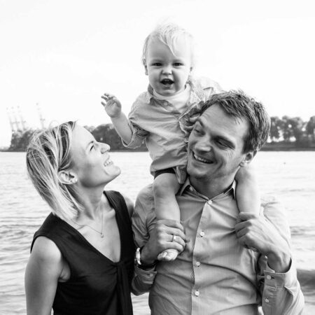 baby auf den schultern seines vaters, mama lcht zu ihm hoch, an der elbe
