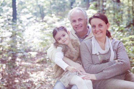 eltern mit kindergartenkind im wald, gemütlich auf waldboden sitzend