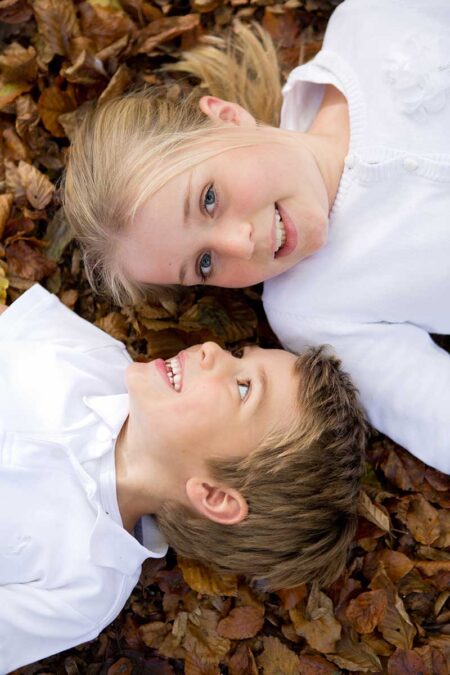 bruder und schwester liegen auf einem laubigen waldboden, schönes portrait