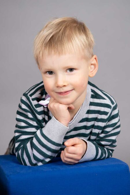 studioportrait eines kleinen jungen mit streifenpulli, der in die kamera schaut