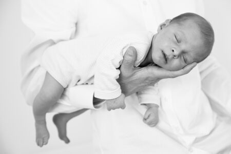 neugeborenes baby in weiß vor weiß im flieger beim papa auf dem arm