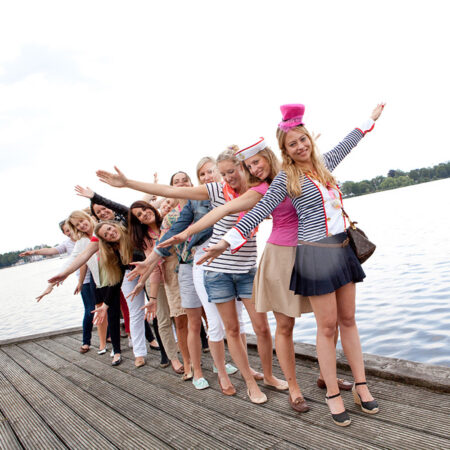 Gruppe von bunten jungen frauen auf einem JGA machen an der alster eine flieger-pose
