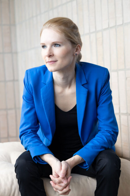 junge frau mit blauem sacko und zopf schaut in die ferne
