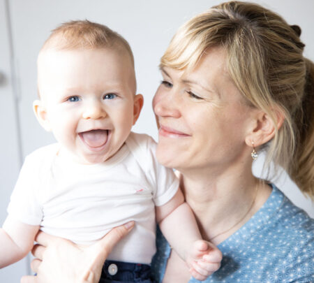 baby lachend auf mamas arm, die ihn liebevoll anschaut