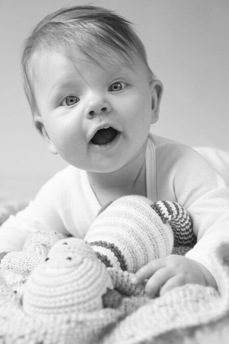 lachendes baby mit kuscheltier in schwarz-weiß