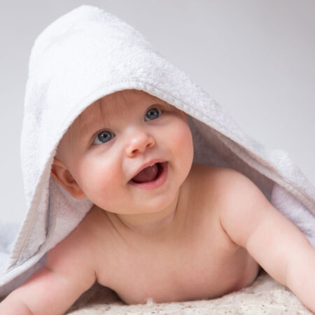 baby lacht unter badekaputze hervor