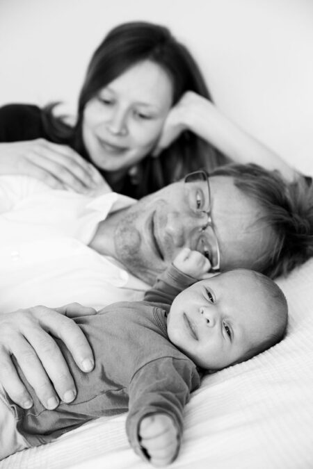 baby mit mama und papa auf dem bett, alle lächeln