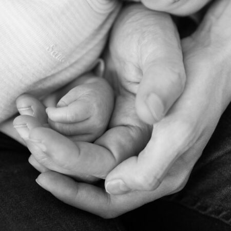 babyhand in händen von mama und papa