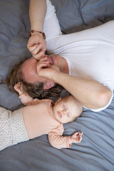 baby und papa liegen auf dem bett, baby schläft, papa reibt sich die augen