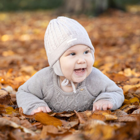 happy baby liegt auf der herbstlichen wiese im stadtpark und lacht