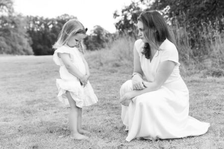 Portrait von Tante und kleinem Mädchen im Park, beide sind im weißen Kleid und machen grimassen