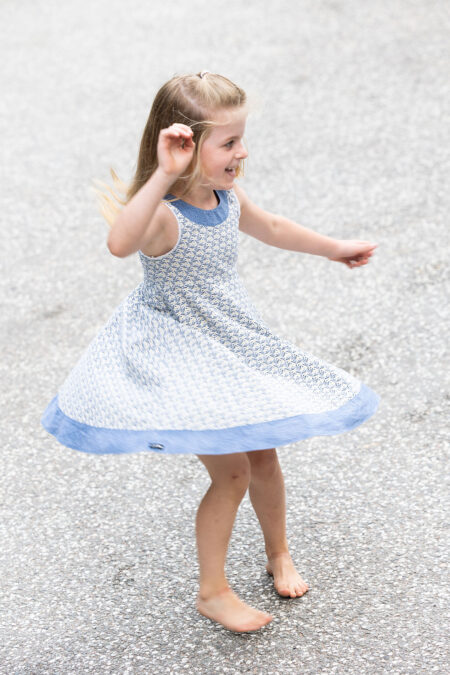 lachendes mädchen dreht sich, so dasss ihr kleid fliegt, natürliches kinderportrait in bewegung
