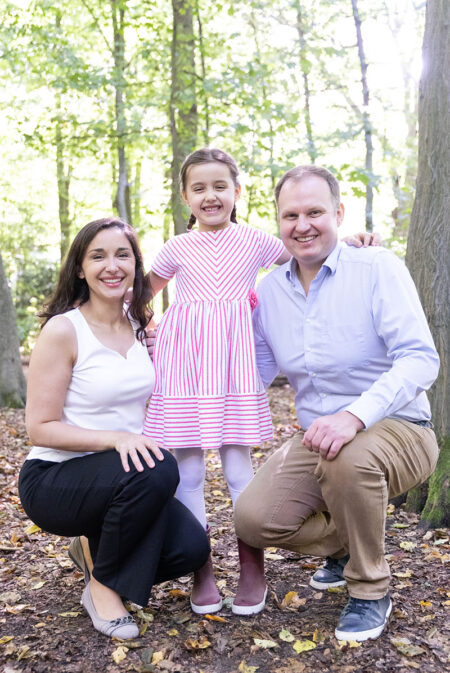 mama und papa mit schulkind im rosa kleid im stadtpark-wald