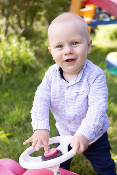 baby lacht am bobbycar in die kamera