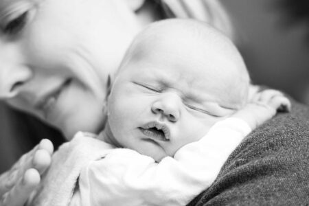portrait eines süßen neugeborenem auf mamas arm