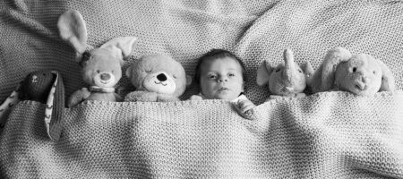 neugeborenes im bett mit kuscheltiere